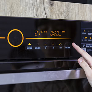 Close up of teenager's hand setting temperature control on oven.