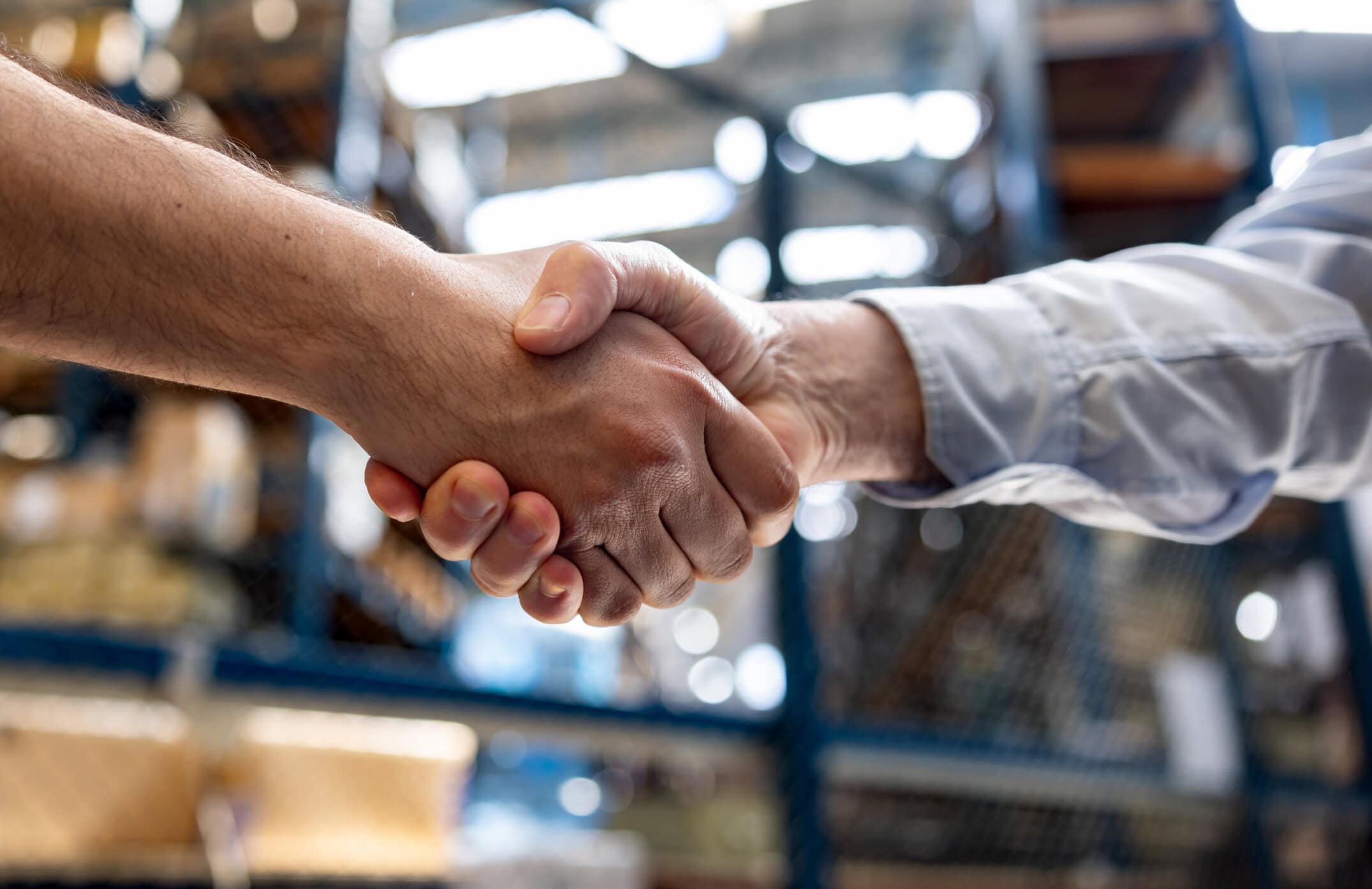 Warehouse manager hiring an employee and handshaking his hand - business concepts