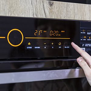 Close up of teenager's hand setting temperature control on oven.