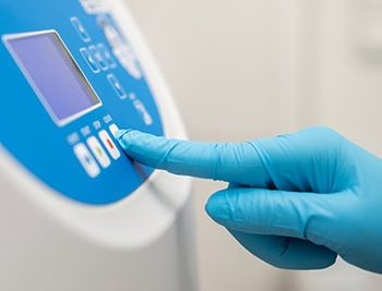 Close up laboratory worker hand in rubber gloves sets parameters on the centrifuge for sample preparation. DNA, oncology marker analysis in the clinical laboratory.