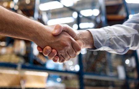 Warehouse manager hiring an employee and handshaking his hand - business concepts